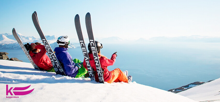 Хлопці та дівчина сидять на горі з лижами Icelantic