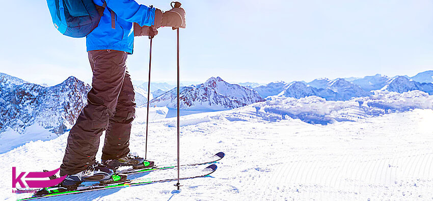Чоловік стоїть на лижах, тримаючи в руках гірськолижні палиці