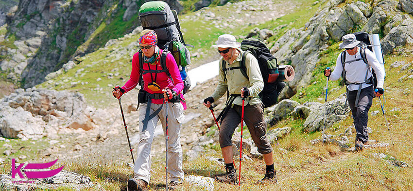Группа туристов с рюкзаками идут по тропе в горах